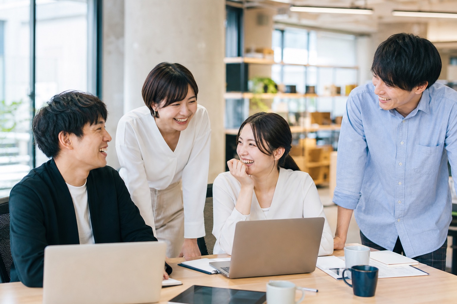 デスクで笑顔を交わす若い日本人チーム