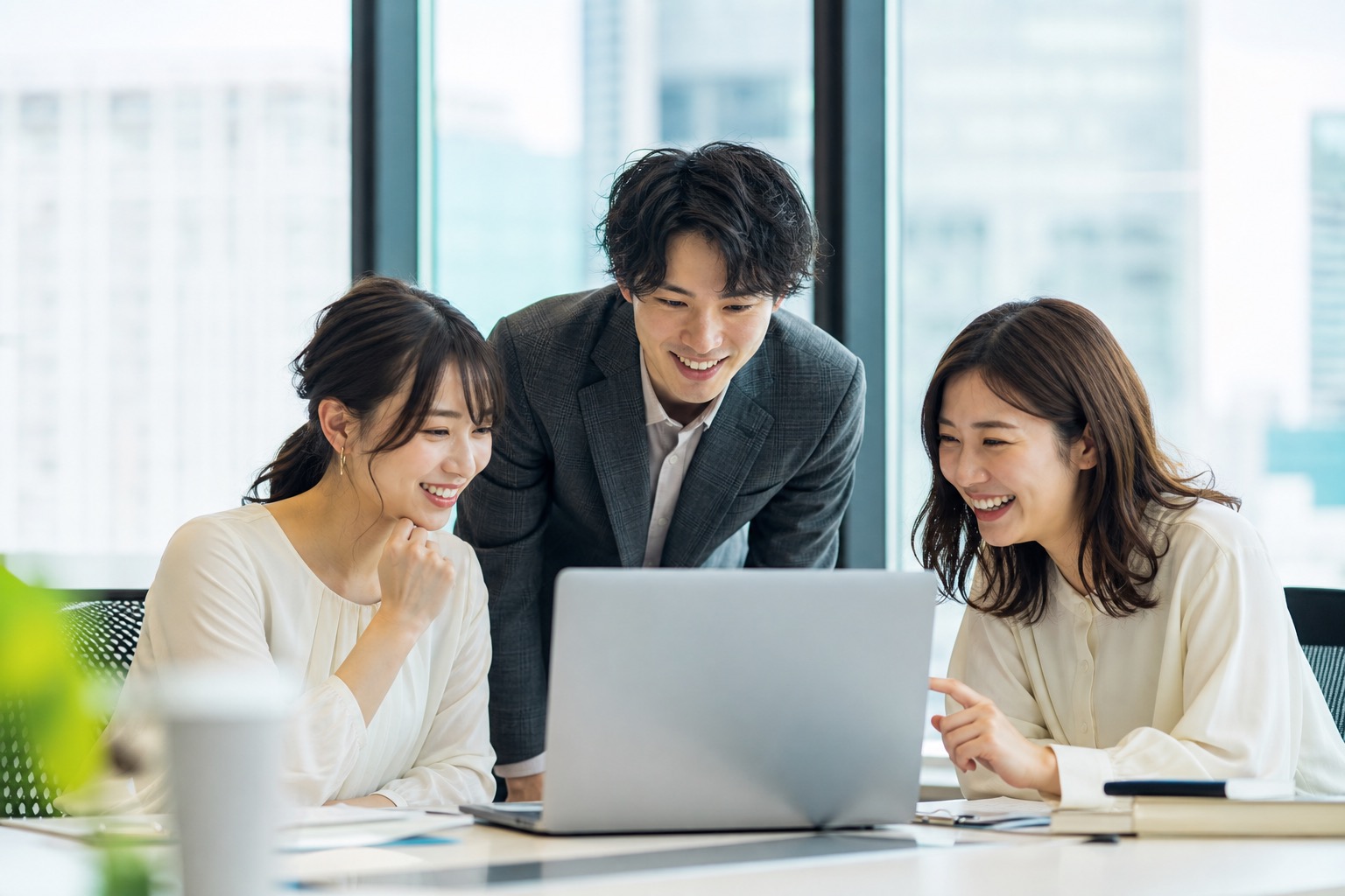 オフィスでノートパソコンを囲み、打ち合わせをする日本人のチーム